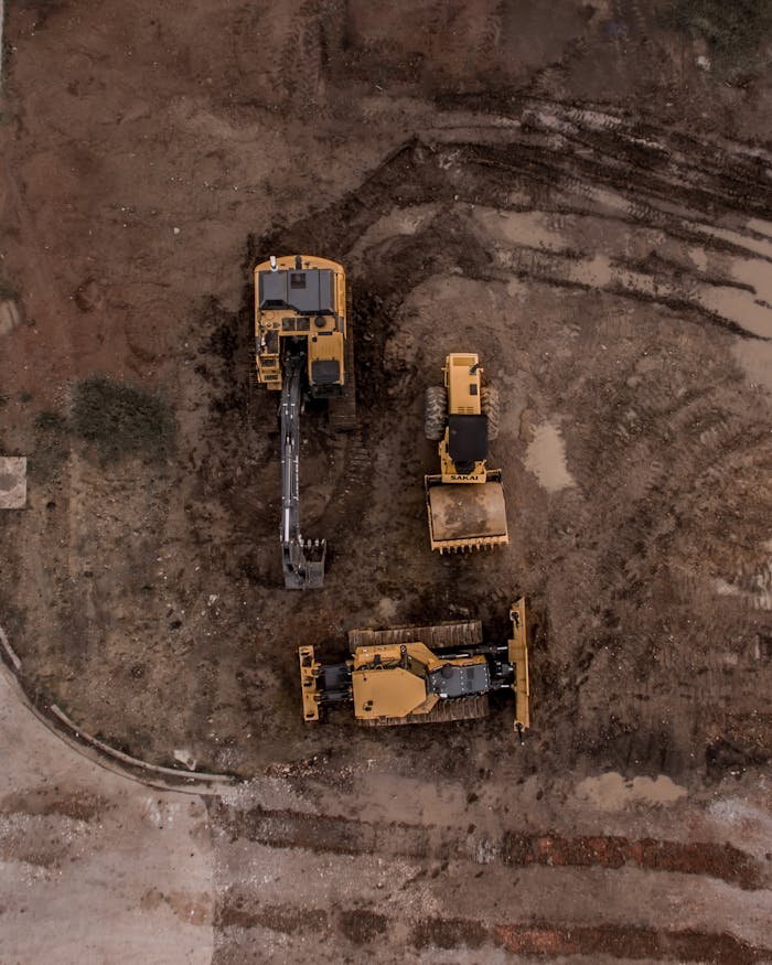 Vista aérea de tres máquinas excavadoras alineadas en un terreno fangoso durante excavaciones expertas en Valencia.