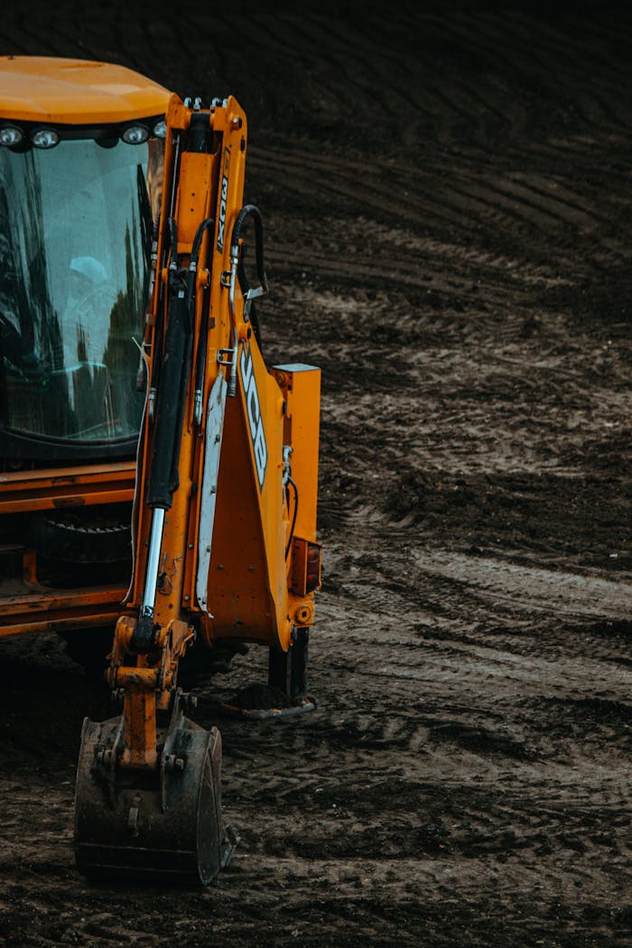 Excavadora estacionada frente a una pila de ladrillos, lista para comenzar una obra de excavaciones expertas en Valencia.