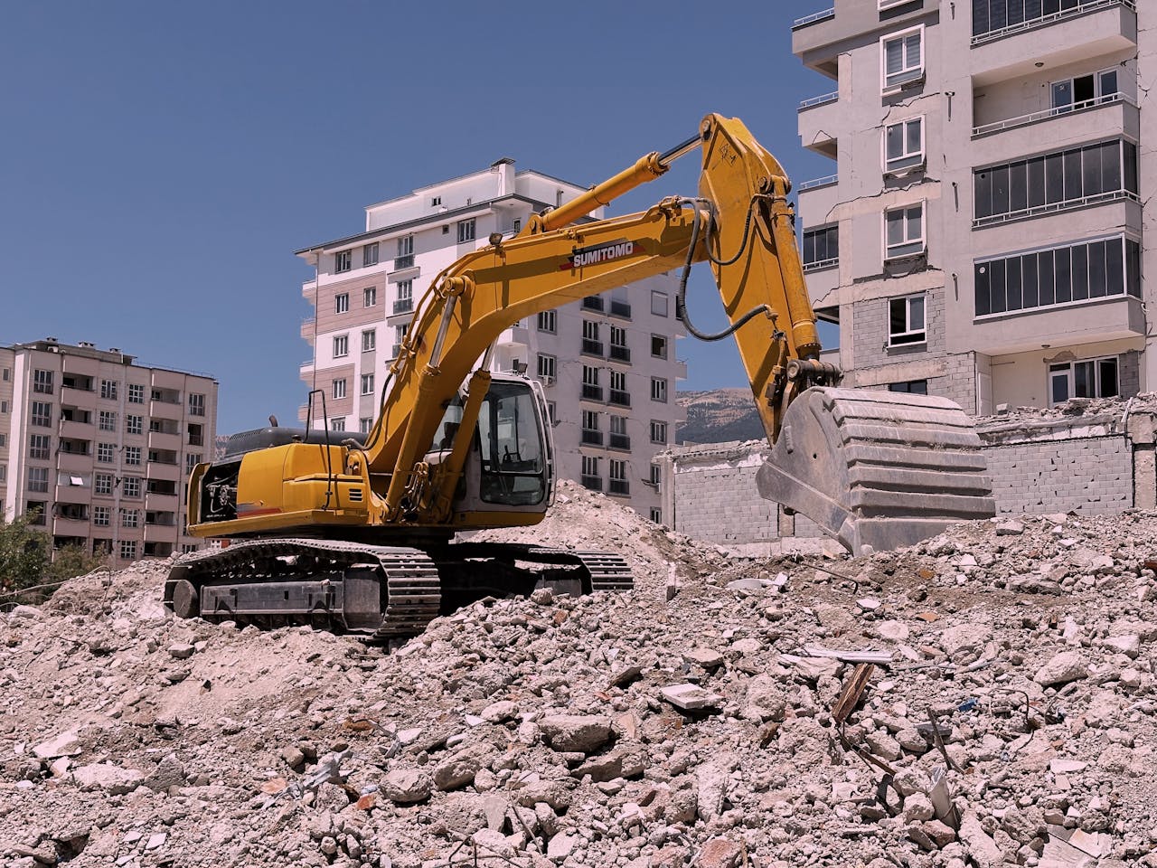 Excavadora hidráulica removiendo escombros de demolición en un entorno urbano como parte de excavaciones expertas en Valencia.