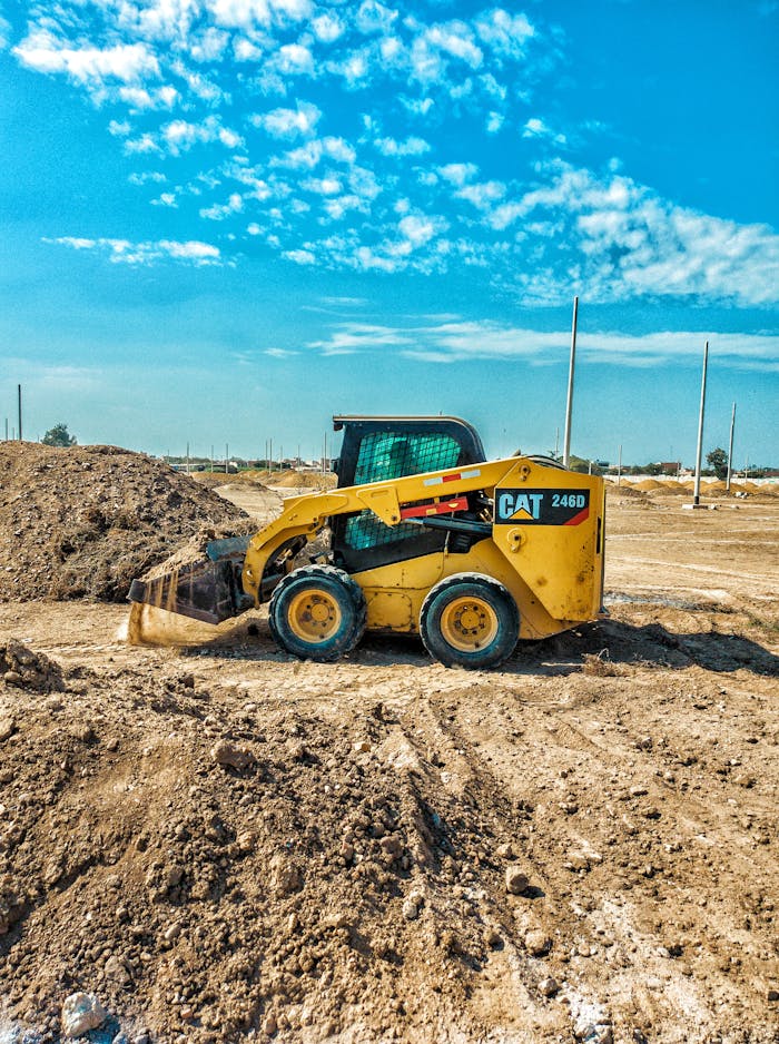 Excavadora estacionada frente a una pila de ladrillos, lista para comenzar una obra de excavaciones expertas en Valencia.